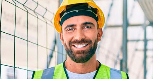 primer plano hombre sonriente con medidas de protección en una obra