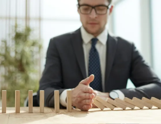 Empresario frenando un dominó en una oficina